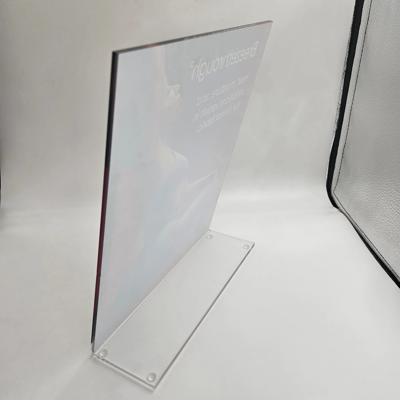 Clear acrylic display holder with a printed card insert, photographed from an angle.