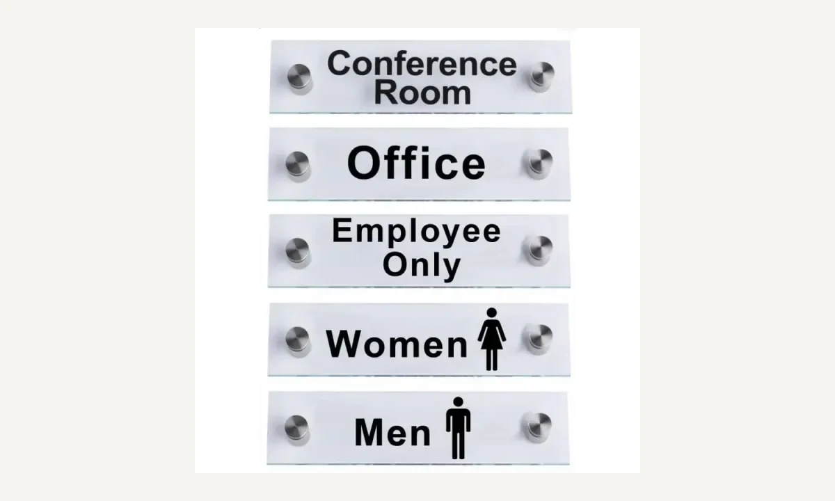 Wall-mounted clear door sign with printed lettering and visible mounting positions.