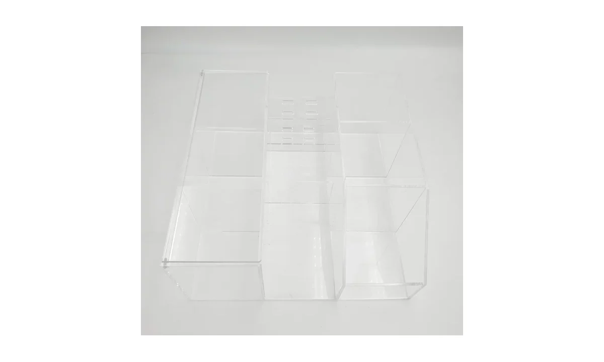 Empty clear acrylic organizer with larger outer compartments and a narrower central slotted section.