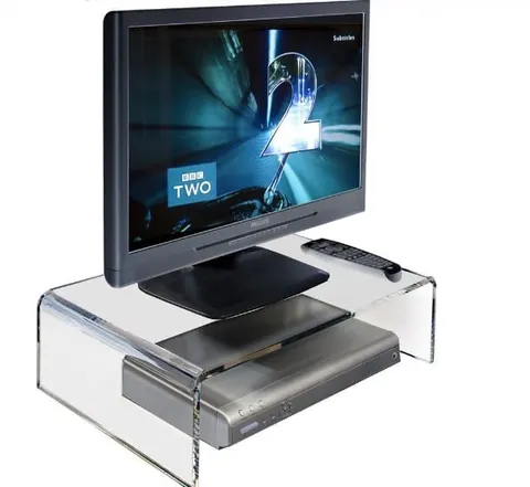 Clear bridge-style acrylic monitor riser above a desk surface