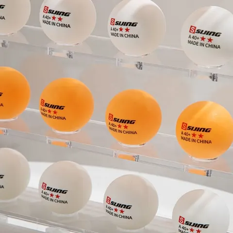 Close-up of golf balls resting in repeated positions on clear display shelves