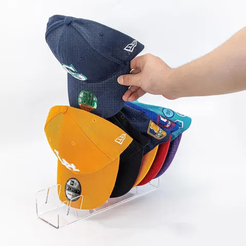 Slotted acrylic cap organizer holding cap brims in a row